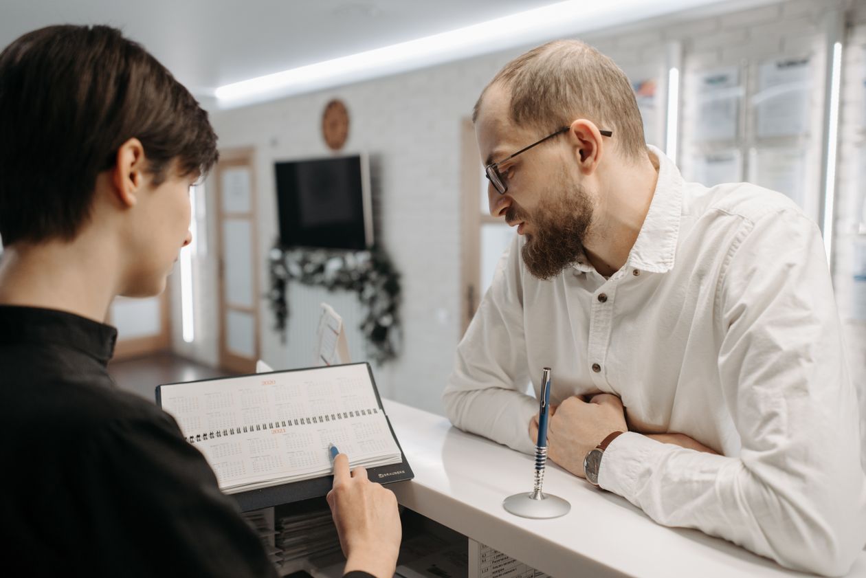 Clinic receptionist confirming an appointment date with a patient at the front desk