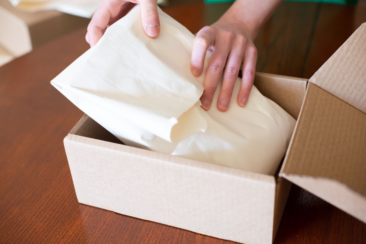 Small business owner packing a customer order into a cardboard box ready for dispatch