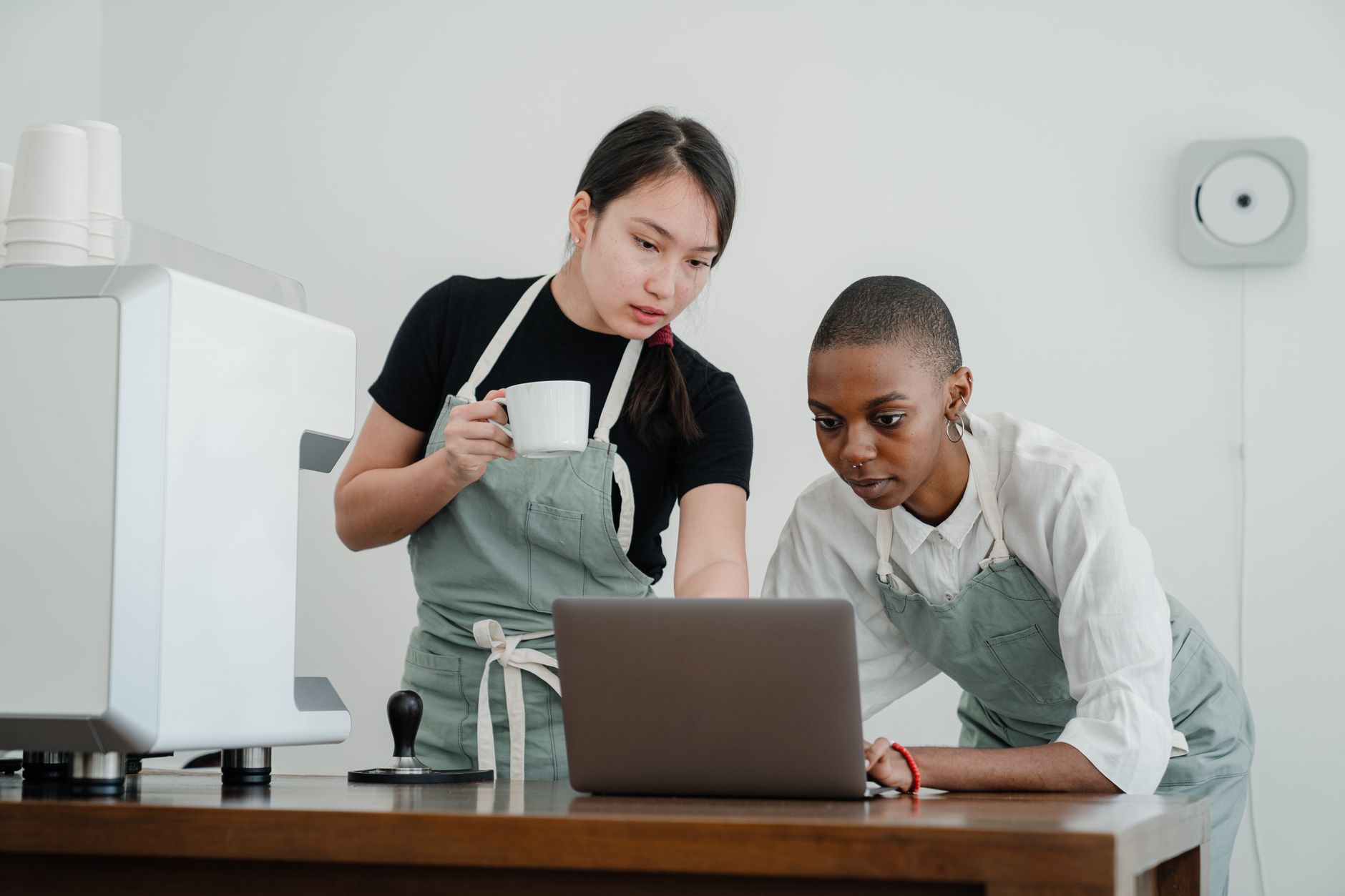 Two cafe workers reviewing AI tools on a laptop, NZ small business