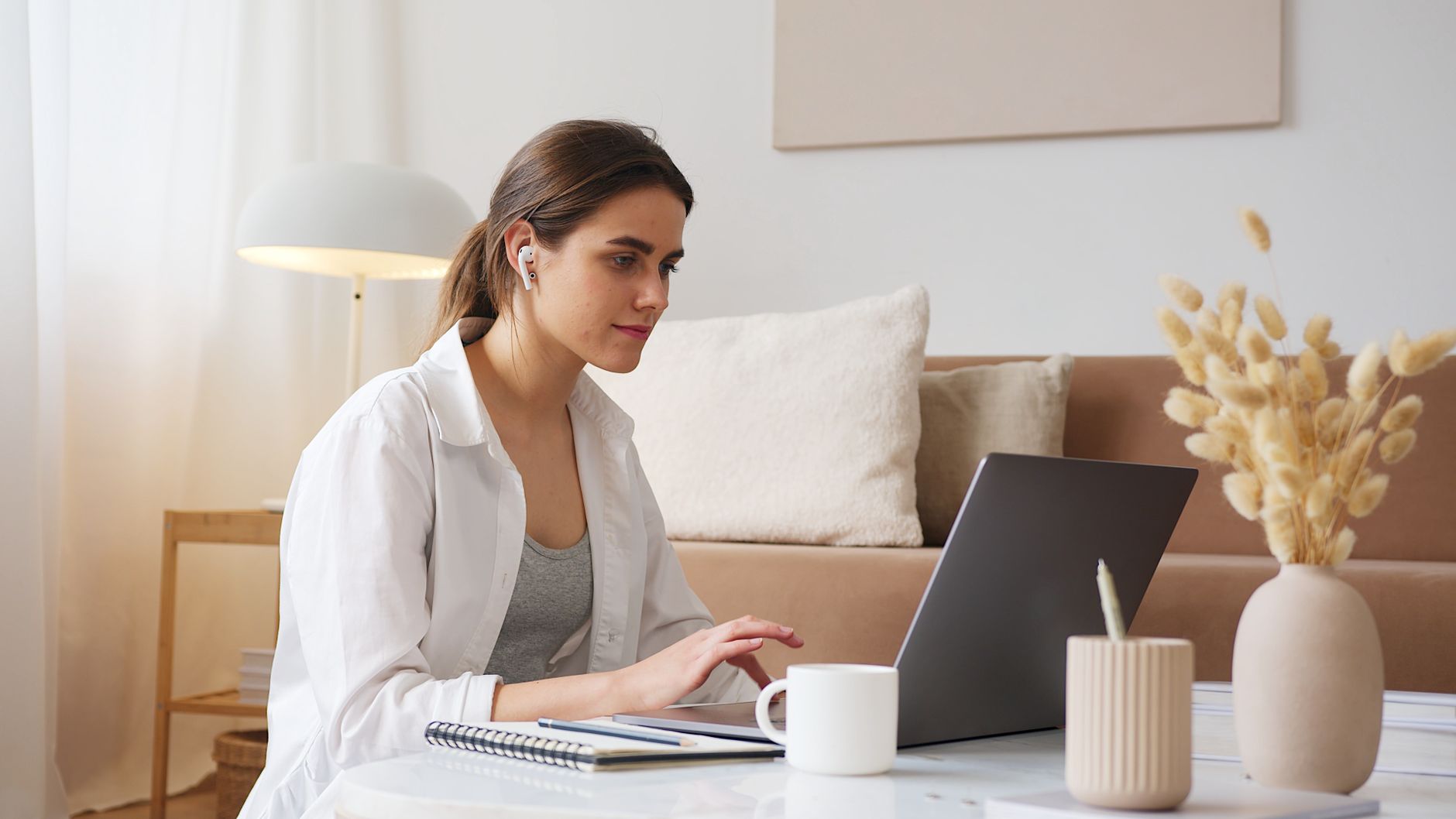 thoughtful woman with earbuds using laptop