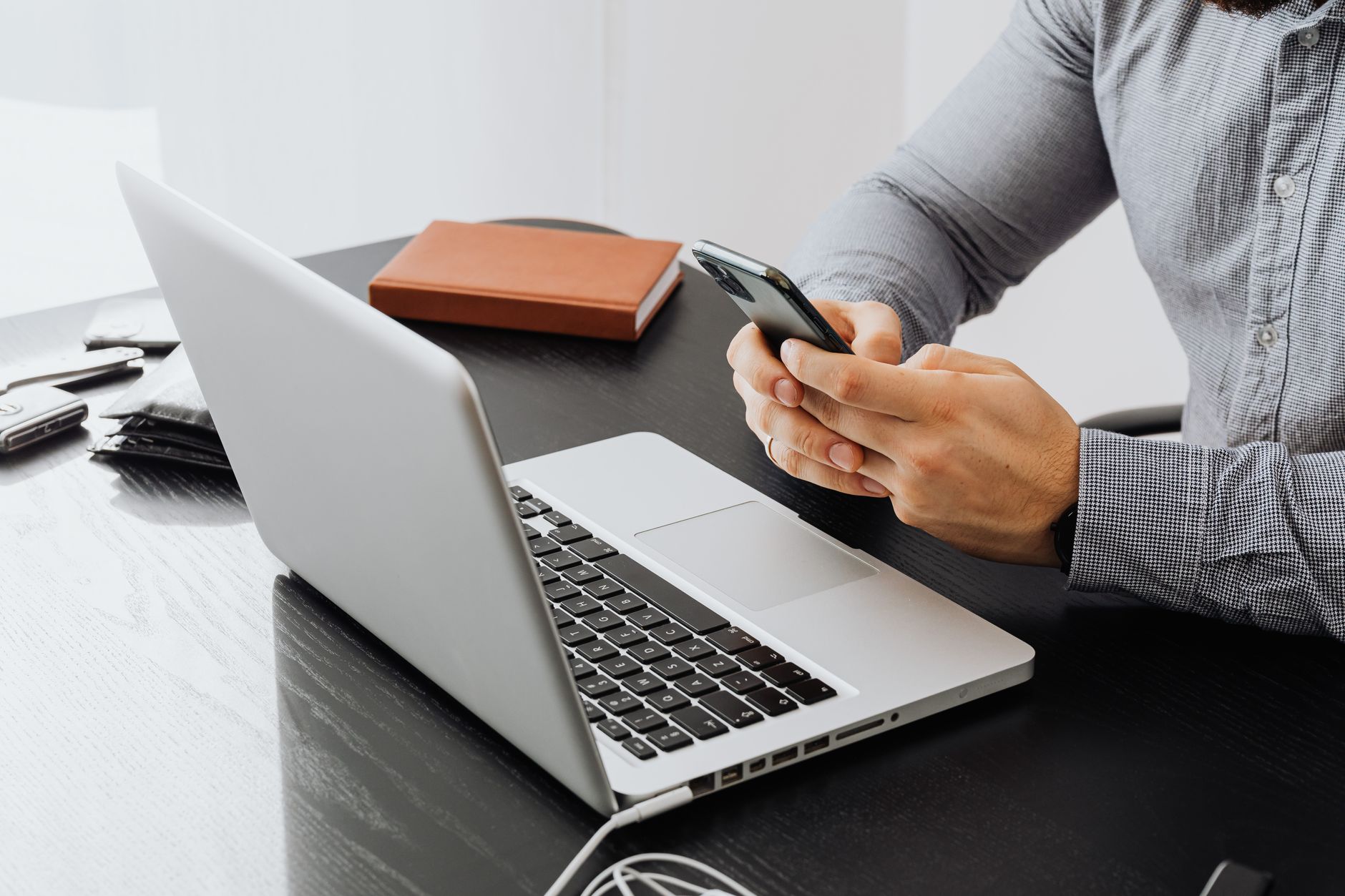 New Zealand business owner checking AI search results on a smartphone above a laptop at a desk